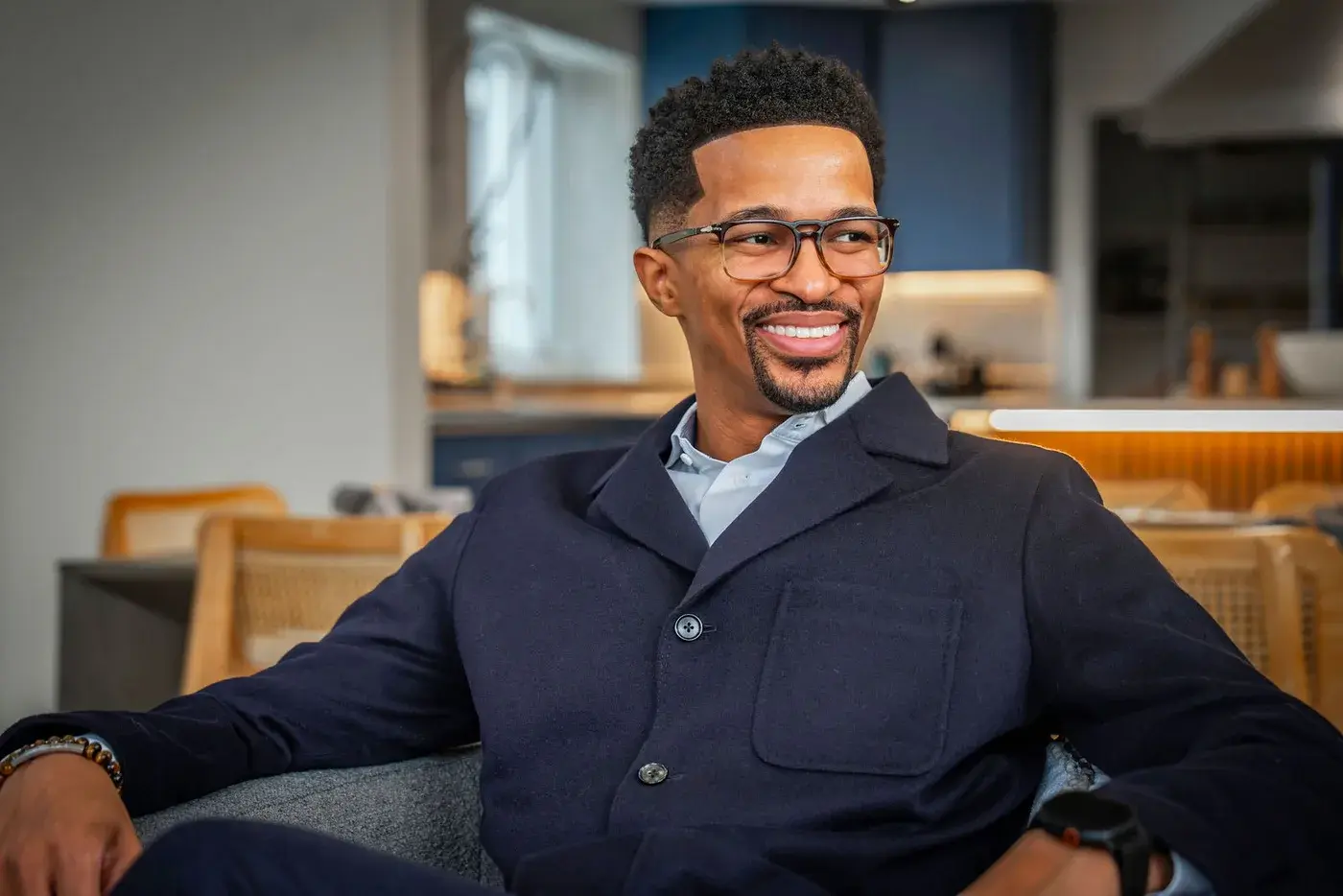 Ryan Leak smiling, seated in a navy jacket